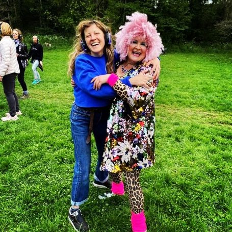 2 women embrace wearing silent disco headsets.